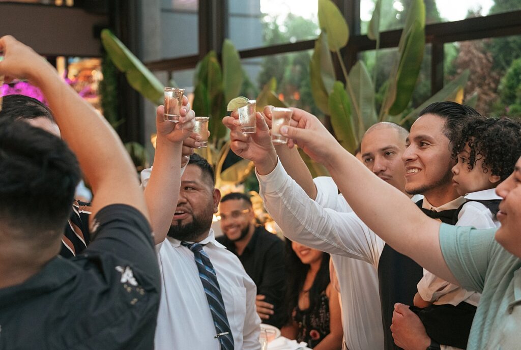 A groom cheers with wedding guests at his Gigante Restaurant wedding in a photo taken by Westchester wedding photographer 