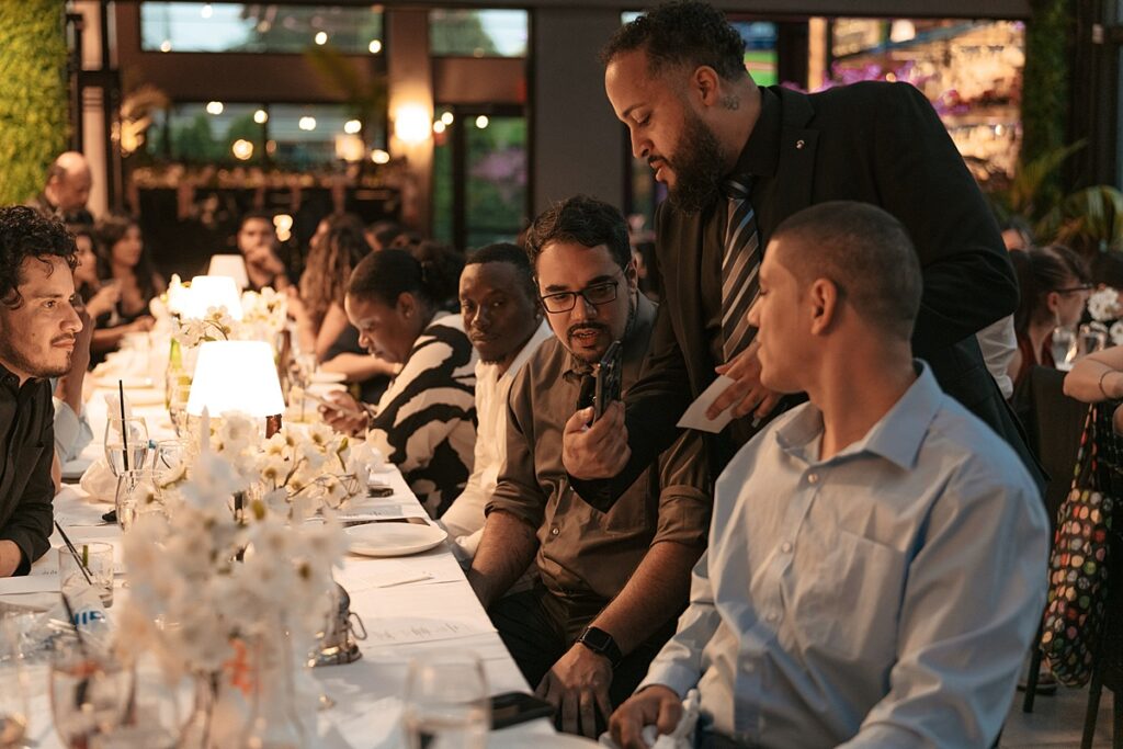 A wedding party seated at a long table is photographed at a Westchester Wedding 