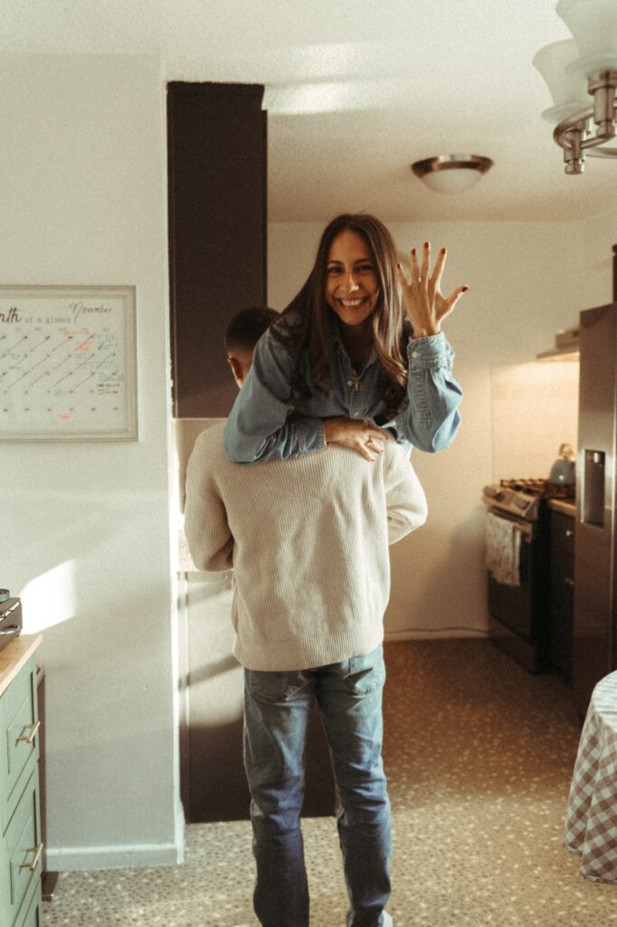 A brunette woman shows off her engagement ring during an in-home New York engagement shoot.