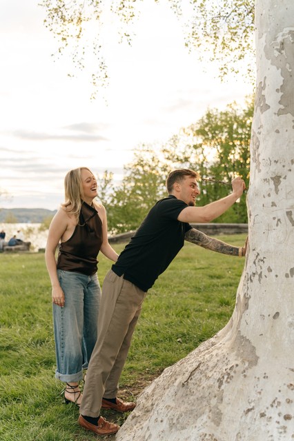 A couple carves their initials into the bark of a tree during new york engagement photos.