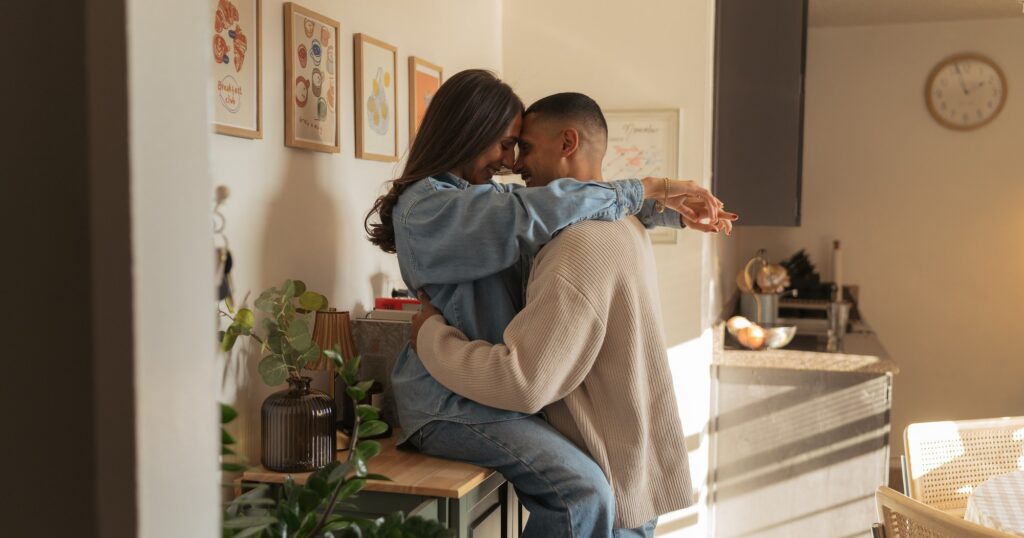 A couple embrace on their kitchen counter during an in-home New York engagement session.