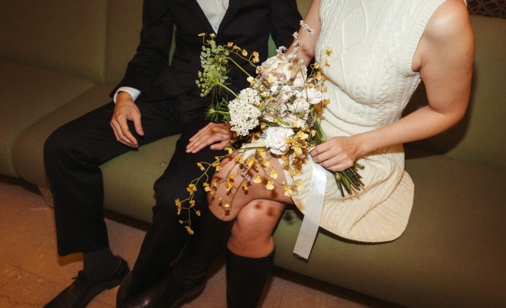 Newlyweds are seated on a green sofa for their NYC elopement photos. 